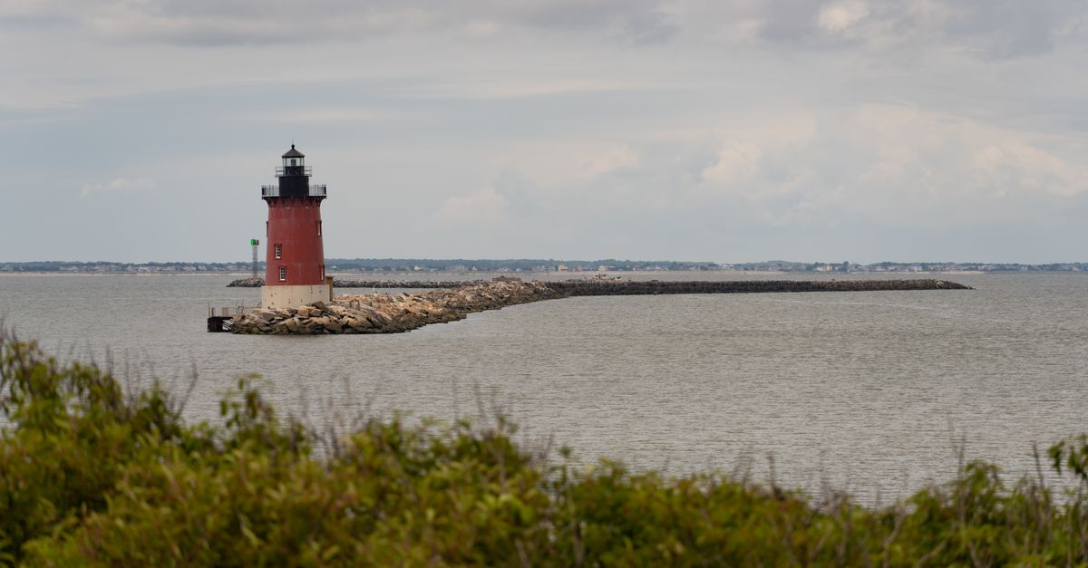 Scenic view of Breakwater Lighthouse in Lewes, Delaware, with dramatic cloudy sky over the sea.